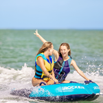 Two young women riding on a blue towable