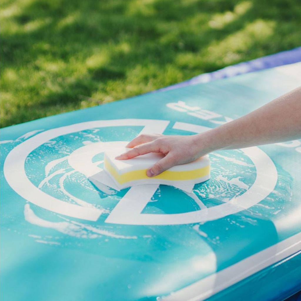 Person holding the scuff eraser xl to wash the paddle board